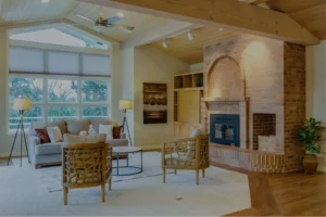 Bright living room featuring a brick fireplace with arched opening, wooden built-in shelving, mid-century modern furniture, and expansive windows overlooking tr