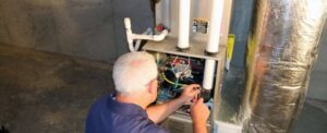Experienced technician performing maintenance on a residential water heater unit with visible piping and electrical components.