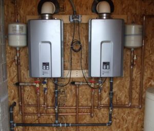 Two silver Rinnai tankless water heaters mounted on plywood with expansion tanks, copper piping, and control panels.