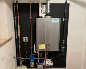 Rinnai tankless water heater mounted on black backdrop with copper piping, blue pump, and Papalia Home Services label visible.