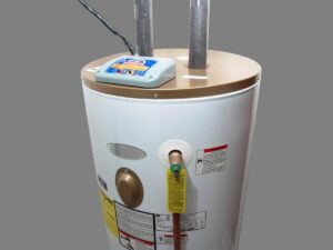 White cylindrical electric water heater with wooden top platform, control panel, temperature gauge, and safety labels visible on the tank.