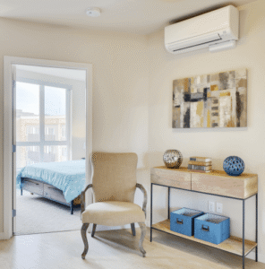Bedroom featuring a ductless mini-split air conditioning unit mounted on the wall above a console table with storage and décor.